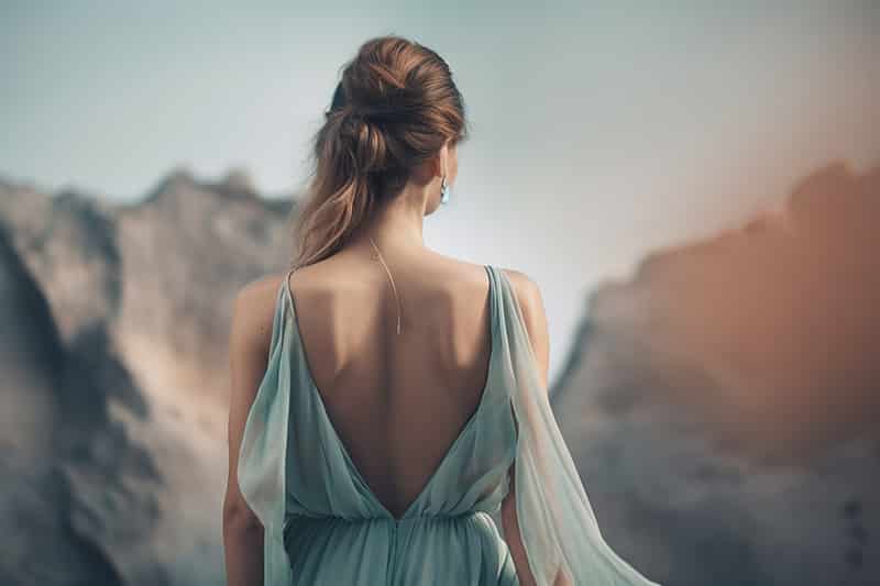 Junge Frau in hellblauem Ballkleid vor einem Gebirge